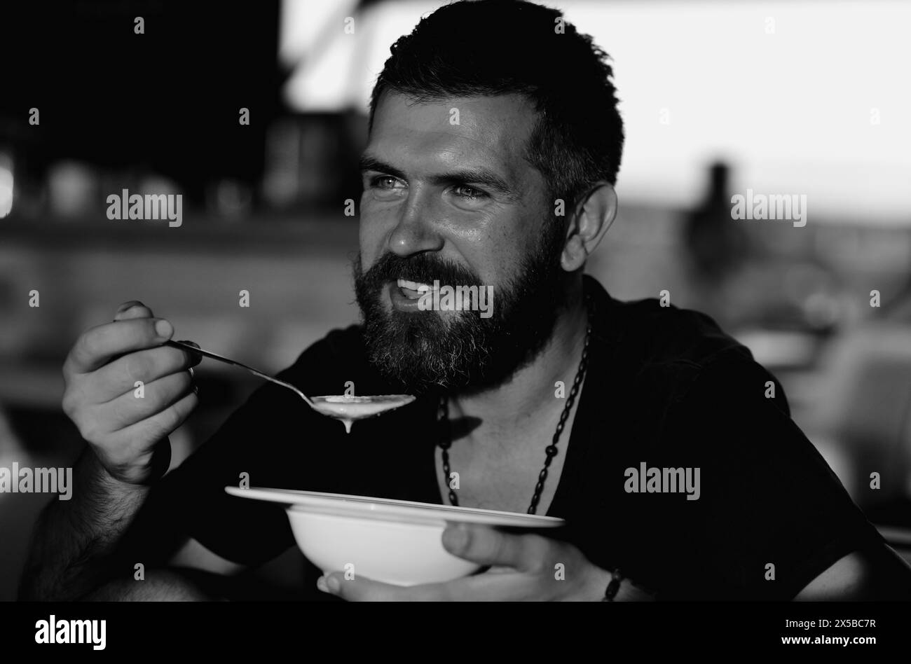 Der Mann isst Suppe. Guter Appetit. Bärtiger Mann mit einer Schüssel Suppe. Glücklicher Kerl, der draußen Suppe isst. Mann isst köstliche Suppe im Restaurant. Abendessen und Mahlzeit Stockfoto