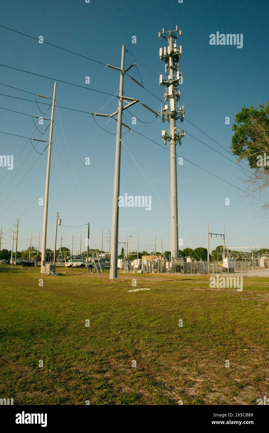 Vertikale Ansicht bei Sonnenuntergang der elektrischen Umspannstation mit Hochspannungsleitungen in St. Petersburg, Florida. Nutzfahrzeuge. Blick auf grünes Gras und blauer Himmel. Stockfoto