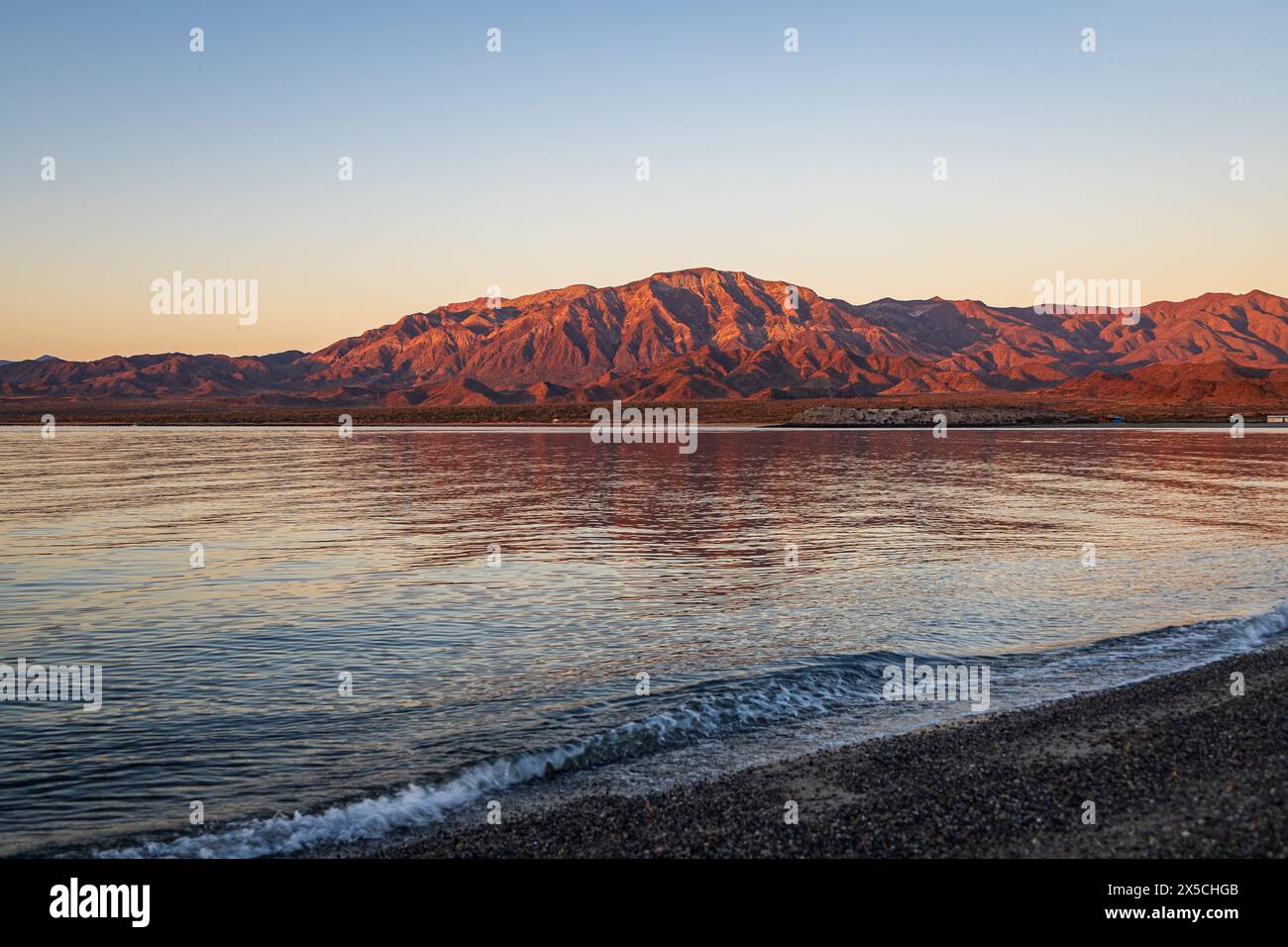 Malerische Landschaft mit ruhigem Wasser und zerklüfteten Bergen bei einem orange-roten Sonnenuntergang in Bahia de los Angeles, Baja California, Mexiko Stockfoto