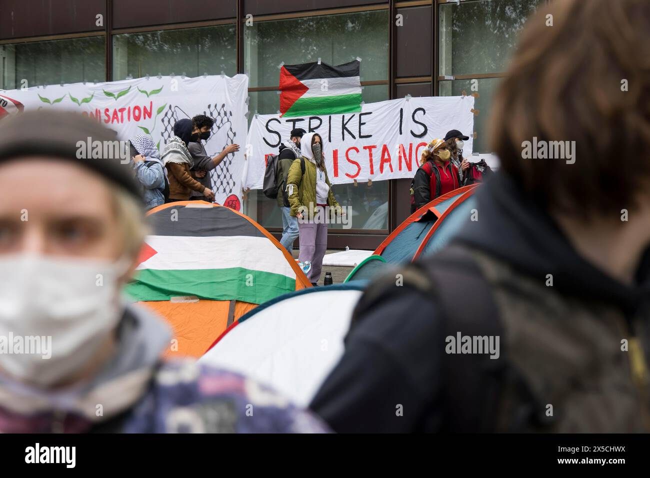 Aktivisten und die Flagge des Staates Palästina während der Besetzung des Hofes der Freien Universität Berlin durch pro-palästinensische Aktivisten. Stockfoto