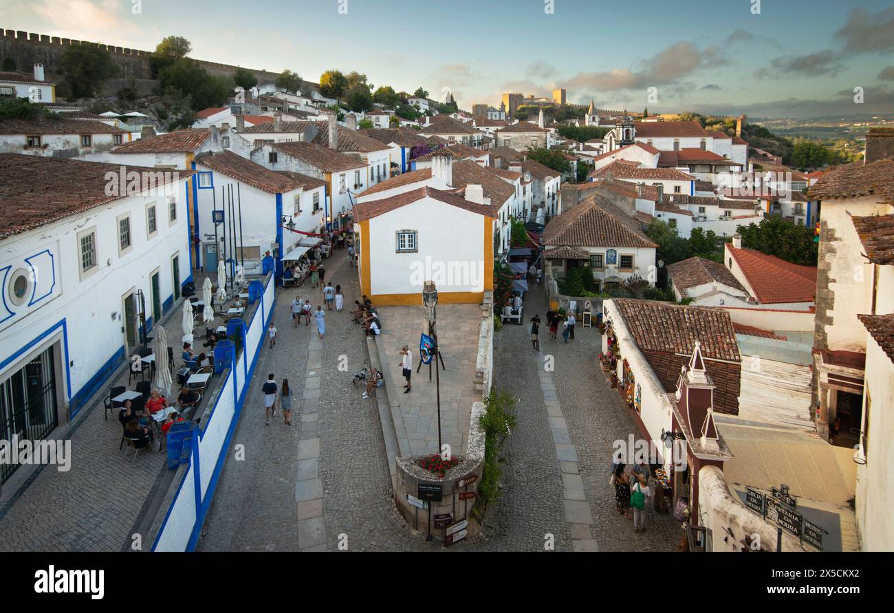 Óbidos, Portugal. Blick nach Norden über den Padrao Camoniano Platz vom Porta da Vila (doppelwandiges Südtor). Die Straße links ist Rua Direita und Rua Josefa de Obidos auf der rechten Seite. Die mittelalterliche Stadt, die seit 308 v. Chr. bewohnt wurde, ist eine der am besten erhaltenen klassischen Mauersiedlungen Portugals mit einer heutigen Bevölkerung von über 3.000 Einwohnern, 100 km nördlich der portugiesischen Hauptstadt Lissabon an der Atlantikküste. Stockfoto