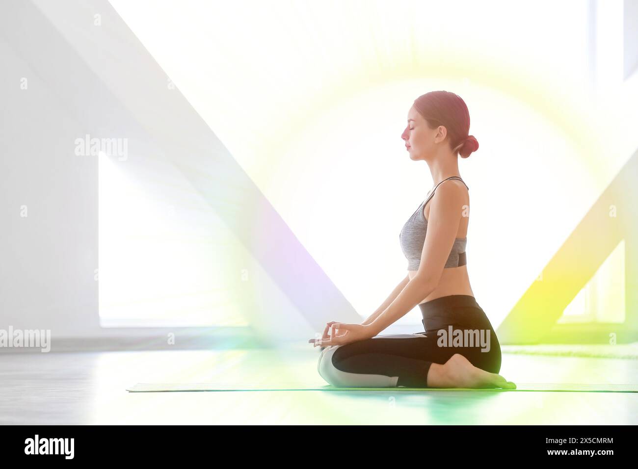 Meditierende junge Frau, die Yoga im Fitnessstudio praktiziert Stockfoto