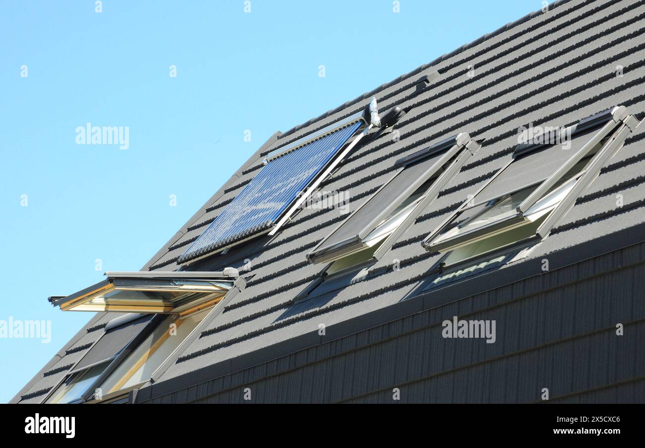 Asphaltschindeln Haus Dach mit Dachfenster, offenen Fenstern, Dachfenster, Solar-Warmwasserbereiter und Solarpaneele. Stockfoto