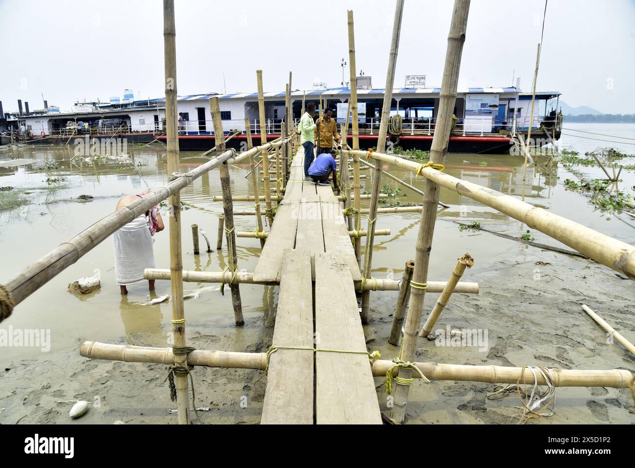 Guwahati, Guwahati, Indien. Mai 2024. Mitarbeiter des Inland Water Department bauen eine vorübergehende Bambusbrücke, um in die Schiffe zu gelangen, nachdem der Wasserstand des Flusses Brahmaputra in Guwahati Indien am Mittwoch, den 8. Mai 2024, plötzlich abgenommen wurde. (Kreditbild: © Dasarath Deka/ZUMA Press Wire) NUR REDAKTIONELLE VERWENDUNG! Nicht für kommerzielle ZWECKE! Stockfoto