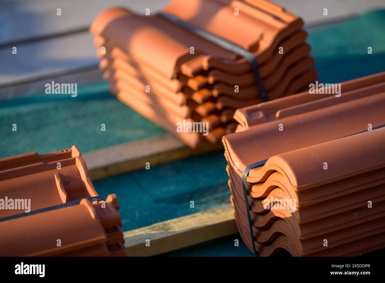 Die Dachziegel aus rotem Lehm sind bereit für die Montage auf der Filz- und Lattenunterlage angeordnet Stockfoto