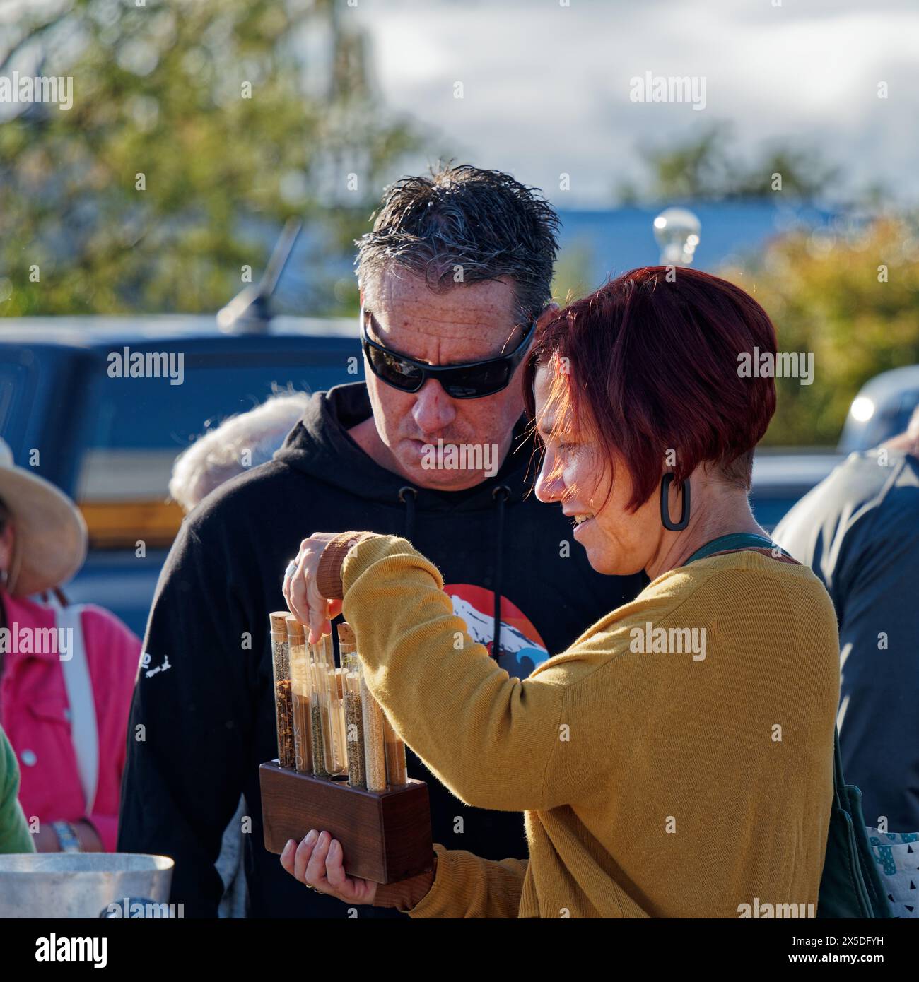Mapua, Region Tasman, Südinsel, Aotearoa / Neuseeland - 1. April 2024: Eine Frau, die ein Reagenzglasgestell auf einem Marktstand bewundert. Stockfoto