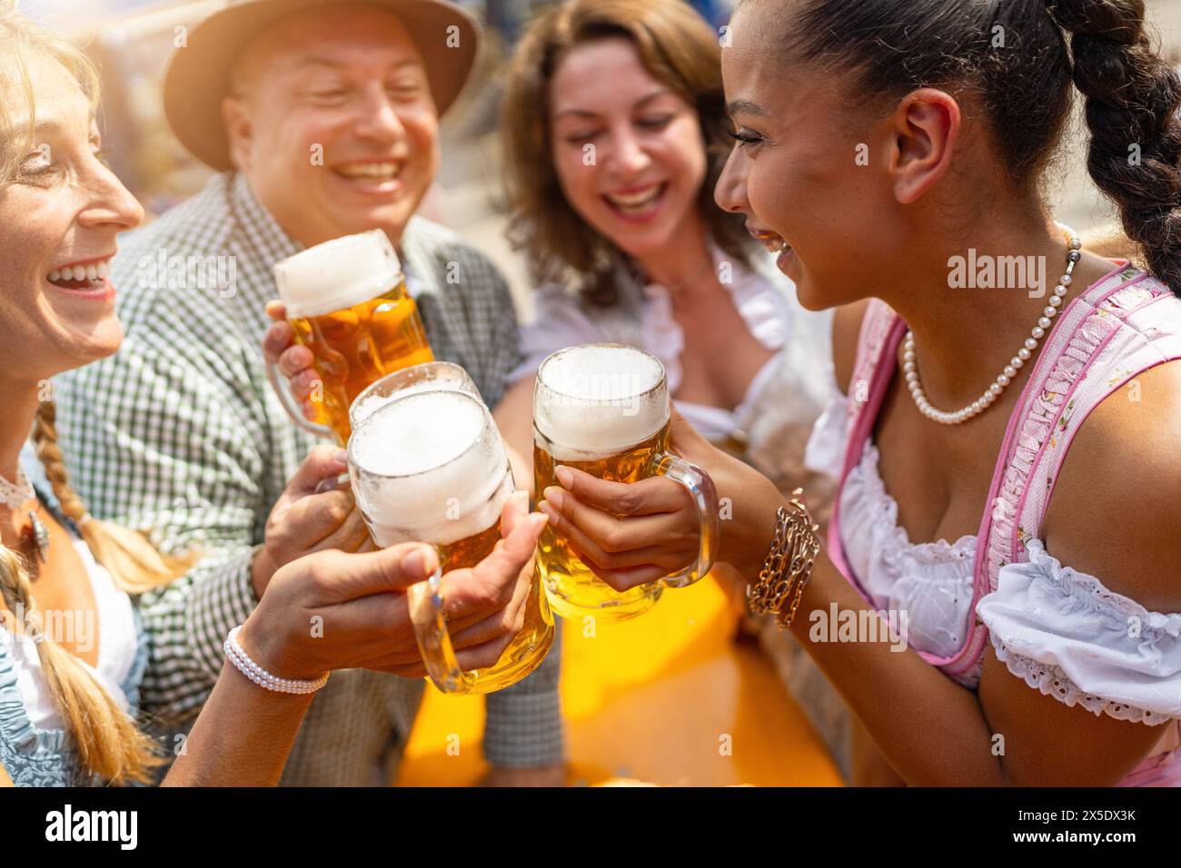 Eine Gruppe von Freunden in traditioneller bayerischer Kleidung, die auf dem Oktoberfest oder Dult in deutschland fröhlich mit Bierbecher toasten Stockfoto