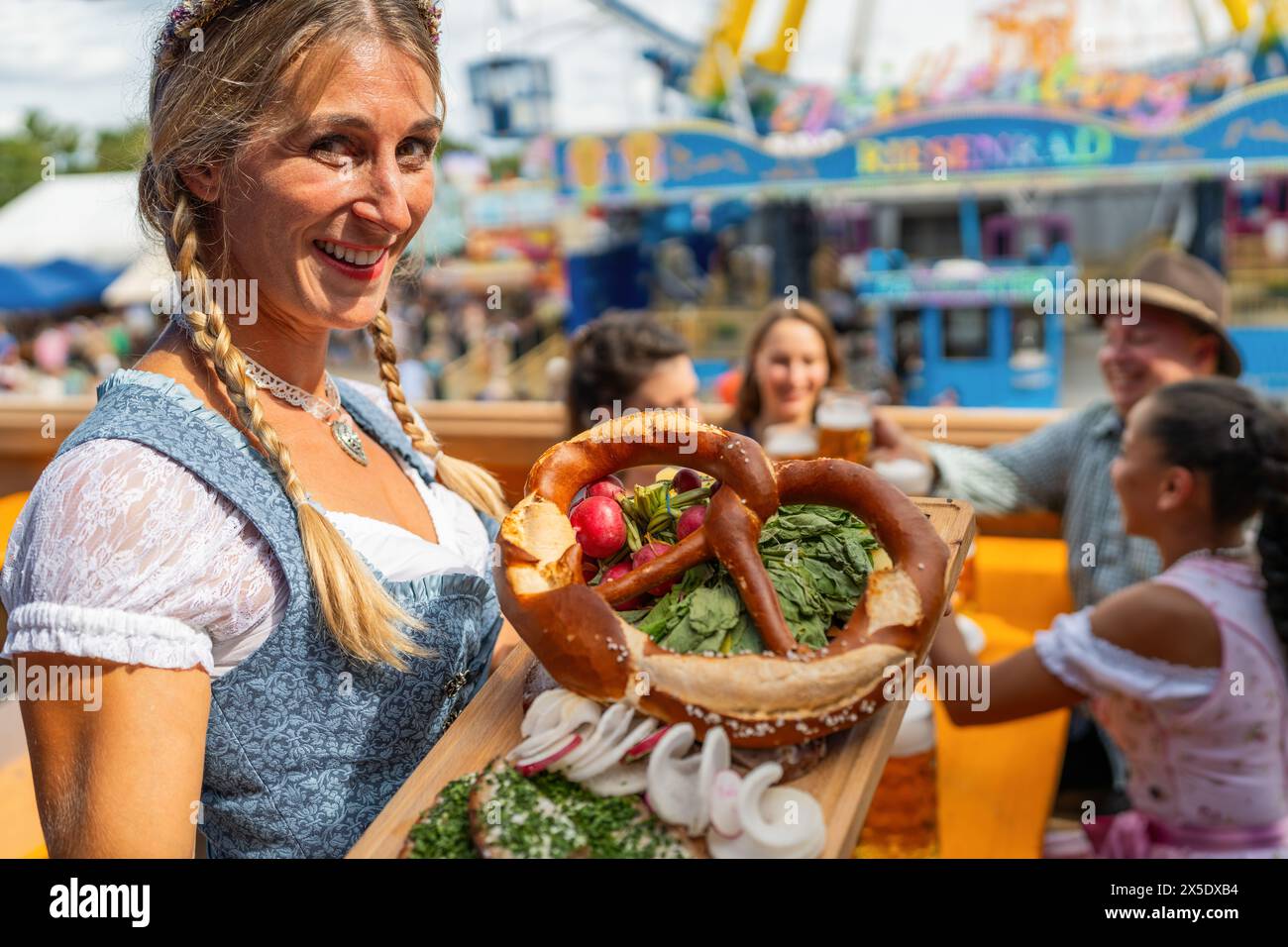 Im oktoberfest in Bayern, Deutschland: Bier und Snacks werden von einer lächelnden Kellnerin in bayerischer Tracht oder Dirndl serviert Stockfoto