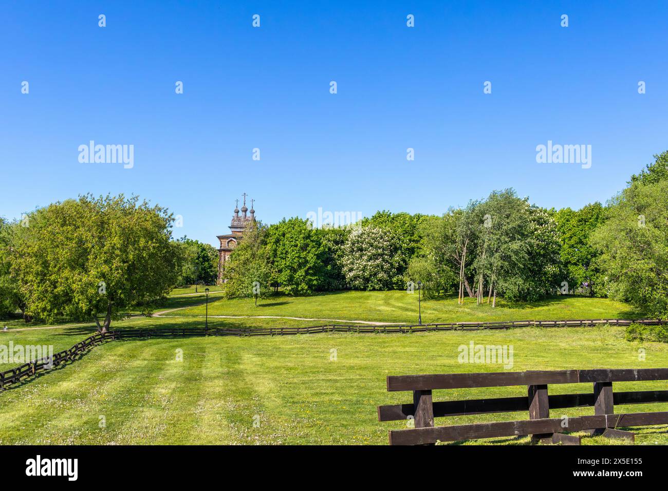 Frühlingsgrüne Landschaft mit Holztempel und Zaun. Stockfoto