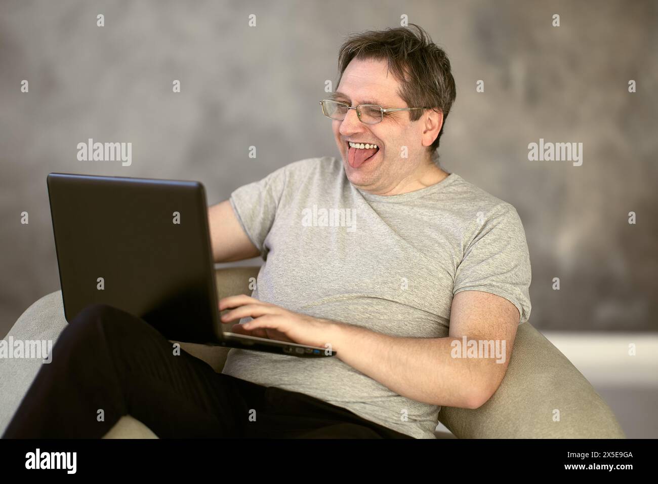 Ein Mann in seinen 50ern arbeitet von zu Hause aus mit einem Laptop, der mit dem Internet verbunden ist. Stockfoto