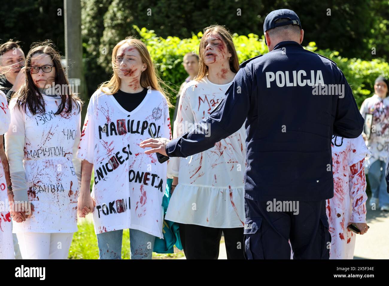 Ukrainische Frauen gemalt in rotem Protest als russische Botschafterin in Polen kommt, um Blumen auf dem Mausoleum des sowjetischen Soldatenfriedhofs am russischen Siegtag, 9. Mai 2024 in Warschau, Polen, zu legen. Die hohe Sicherheit war mit dem russischen Botschafter anwesend. Ukrainische Demonstranten demonstrierten, als der russische Botschafter ankam. Stockfoto