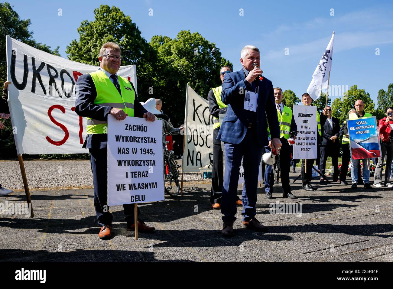 Prorussische Demonstranten stehen, als der russische Botschafter am russischen Siegtag am 9. Mai 2024 in Warschau, Polen, am Mausoleum des sowjetischen Soldatenfriedhofs Blumen legt. Die hohe Sicherheit war mit dem russischen Botschafter anwesend. Ukrainische Demonstranten demonstrierten als russischer Botschafter ankam. Stockfoto