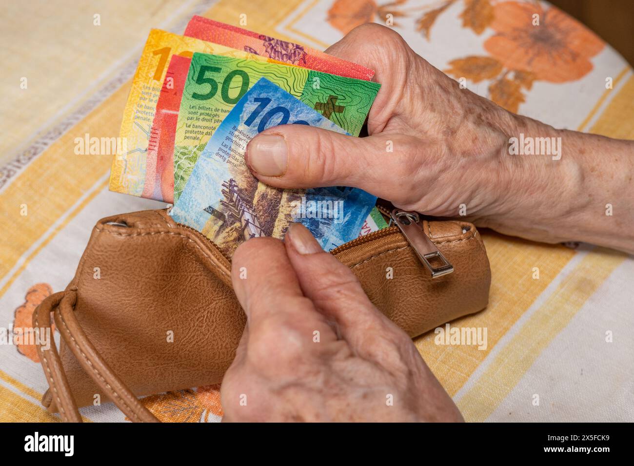 Eine Rentnerin aus der Schweiz betrachtet den Inhalt ihrer Brieftasche, Schweizer Franken, die Lebenshaltungskosten im Ruhestand Stockfoto