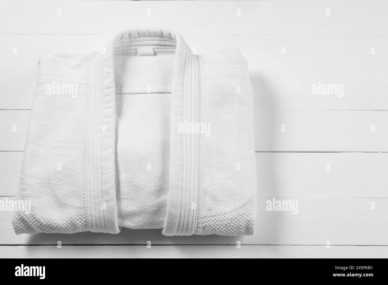Weißer Kimono auf hölzernem Hintergrund, Blick von oben. Leerzeichen für Text Stockfoto