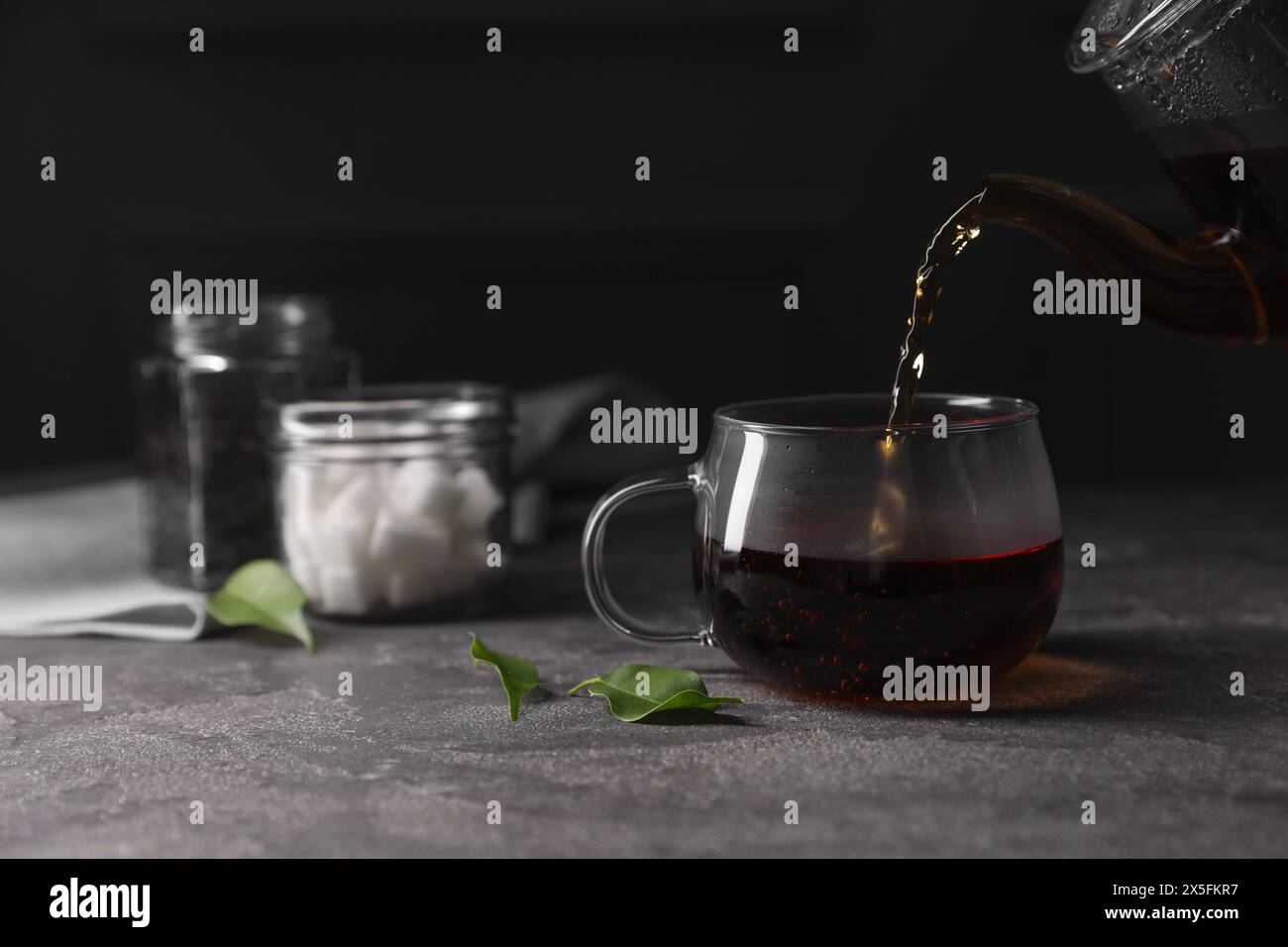 Heißer Tee in eine Tasse auf dem grauen Tisch gießen, Nahaufnahme Stockfoto