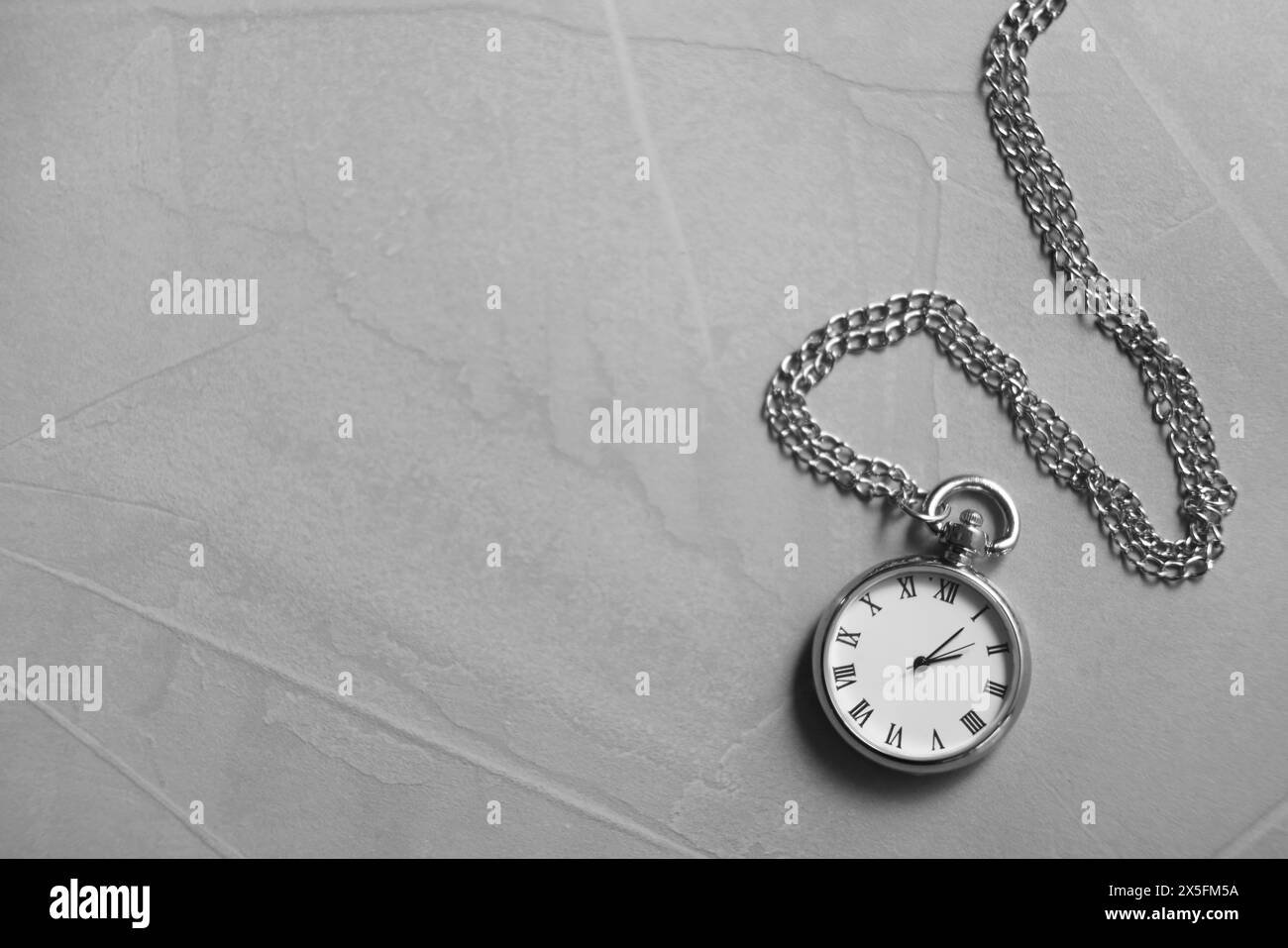 Silberne Taschenuhr mit Kette auf grauem, strukturiertem Tisch, Draufsicht. Leerzeichen für Text Stockfoto