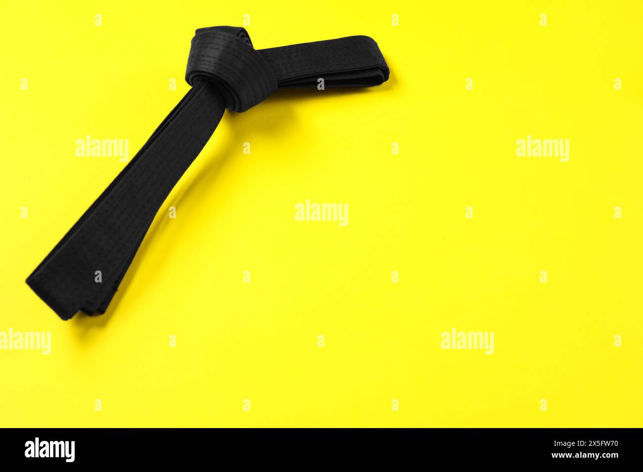 Schwarzer Karate-Gürtel auf gelbem Hintergrund, Platz für Text Stockfoto