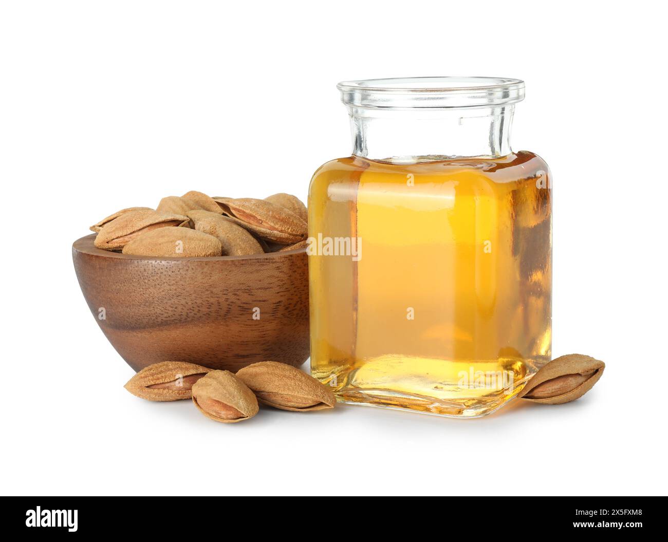 Flasche Mandelöl und frische Nüsse in Schüssel isoliert auf weiß Stockfoto