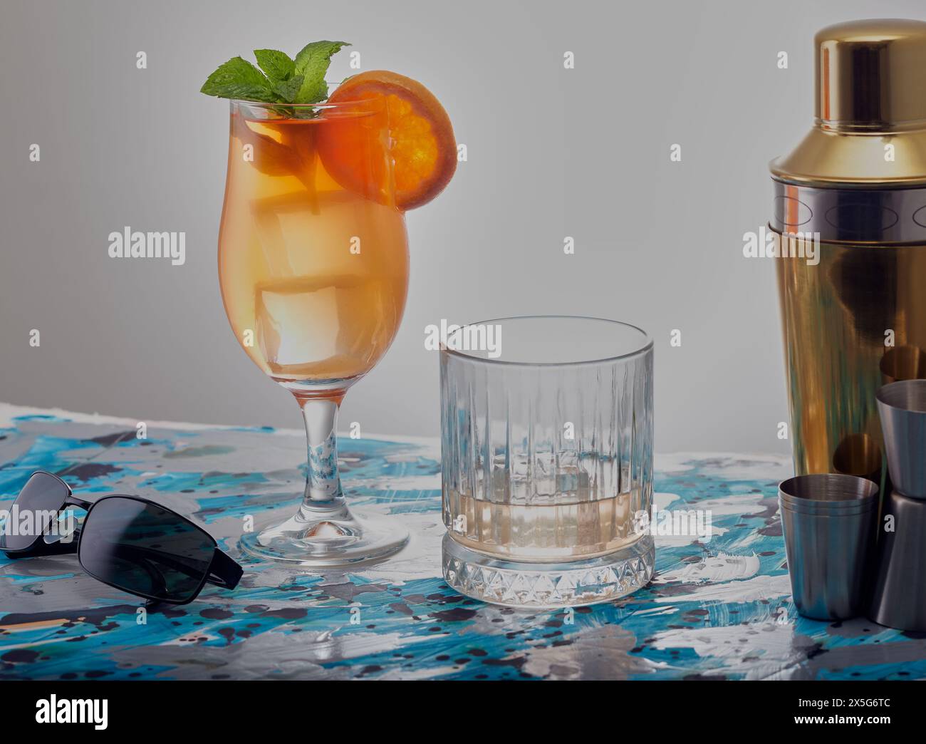 Cocktail und Whisky auf den Felsen mit einer Sonnenbrille an der Seite. Stockfoto