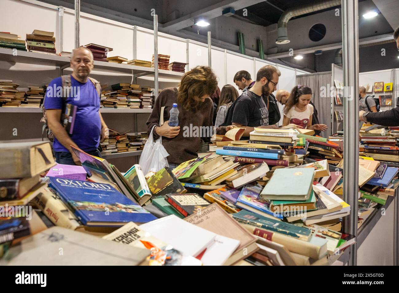 Kunden, die an den Regalen eines Second-Hand-Buchhandels in Belgrad, Serbien, vorbeifahren und alte Bücher, serbisch und Fremdsprache ansehen, die verkauft werden können. Stockfoto
