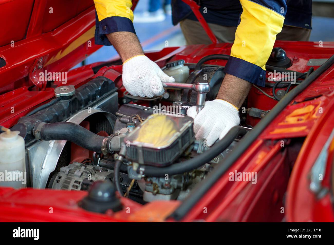 Nahaufnahme Mechaniker Hand in Arbeitsuniform, arbeitet an einem Auto in einer Autowerkstatt oder Garage. Er scheint konzentriert und engagiert in der Diagnose oder Reparatur des ve zu sein Stockfoto