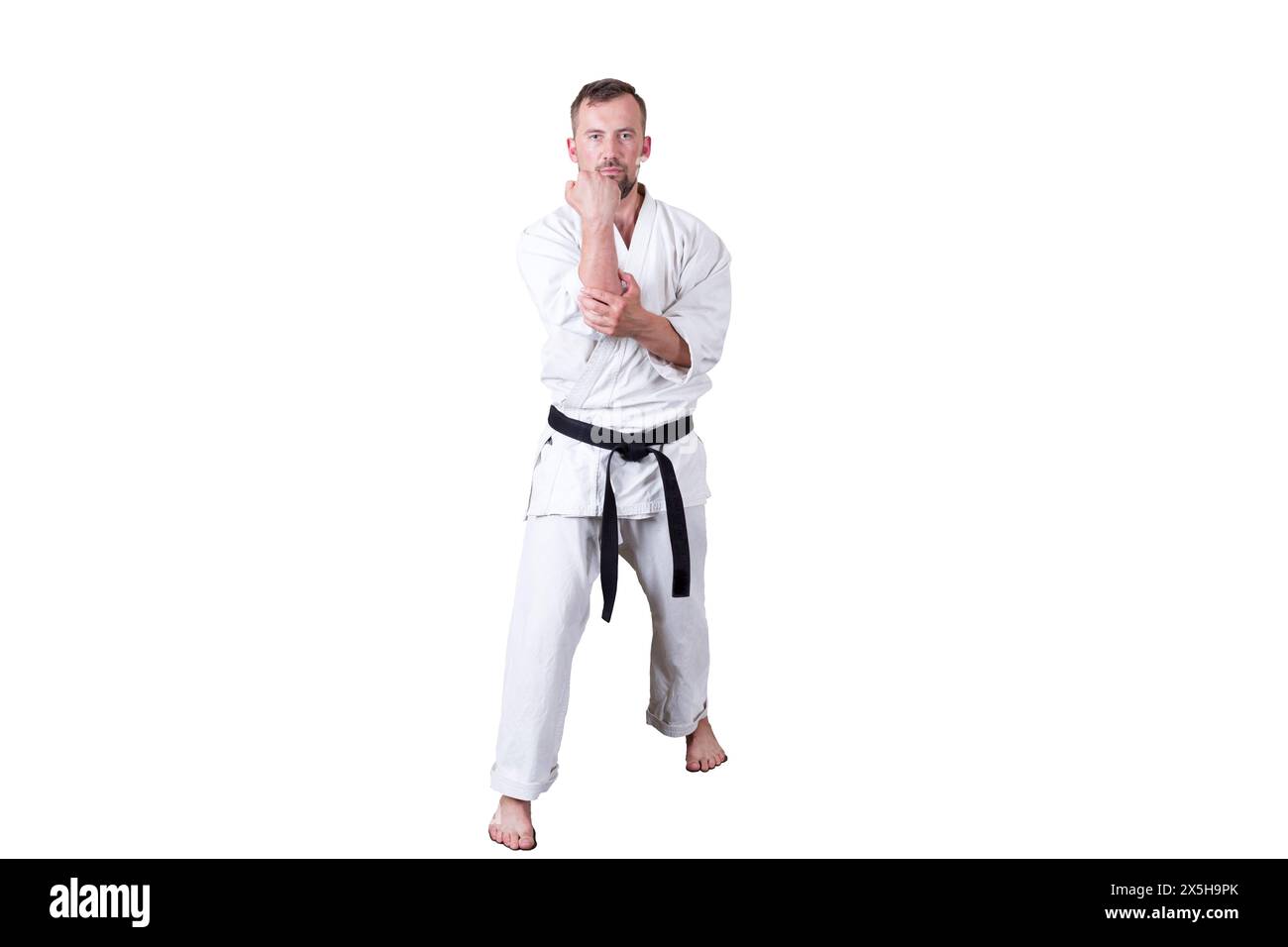 Der Erwachsene Athlet führt formelle goju-ryu-Übungen durch. Sie ist mit einem weißen Hintergrund isoliert. Nahaufnahme. Stockfoto Der Erwachsene Athlet führt formelle goju-ryu-Übungen durch. Sie ist mit einem weißen Hintergrund isoliert. Nahaufnahme. Stockfoto