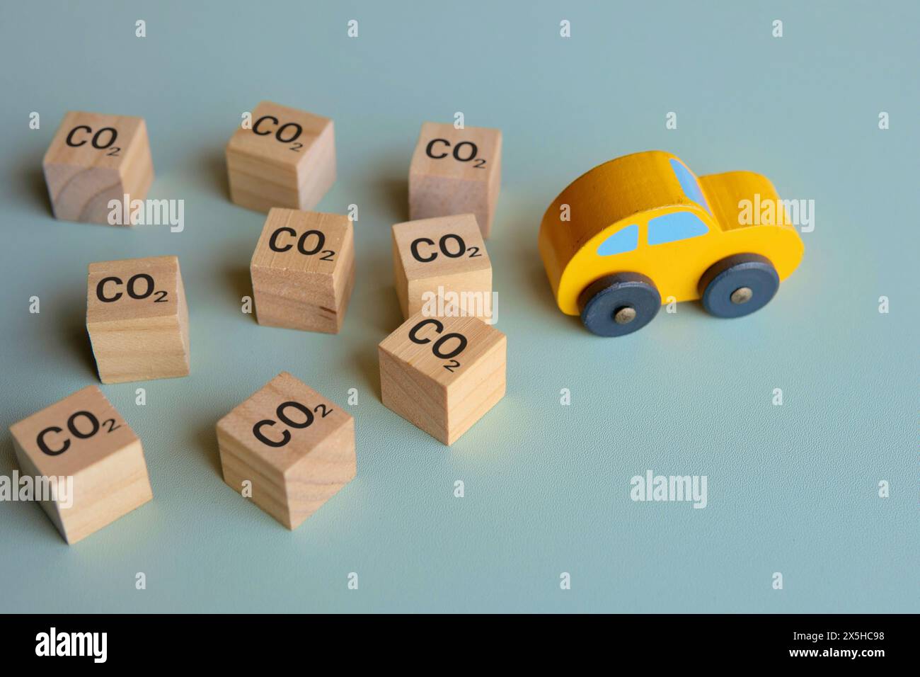 Nahaufnahme eines Autos umgeben von Holzblöcken mit den Buchstaben „CO2“. CO2-Fußabdruck-Konzept. Stockfoto