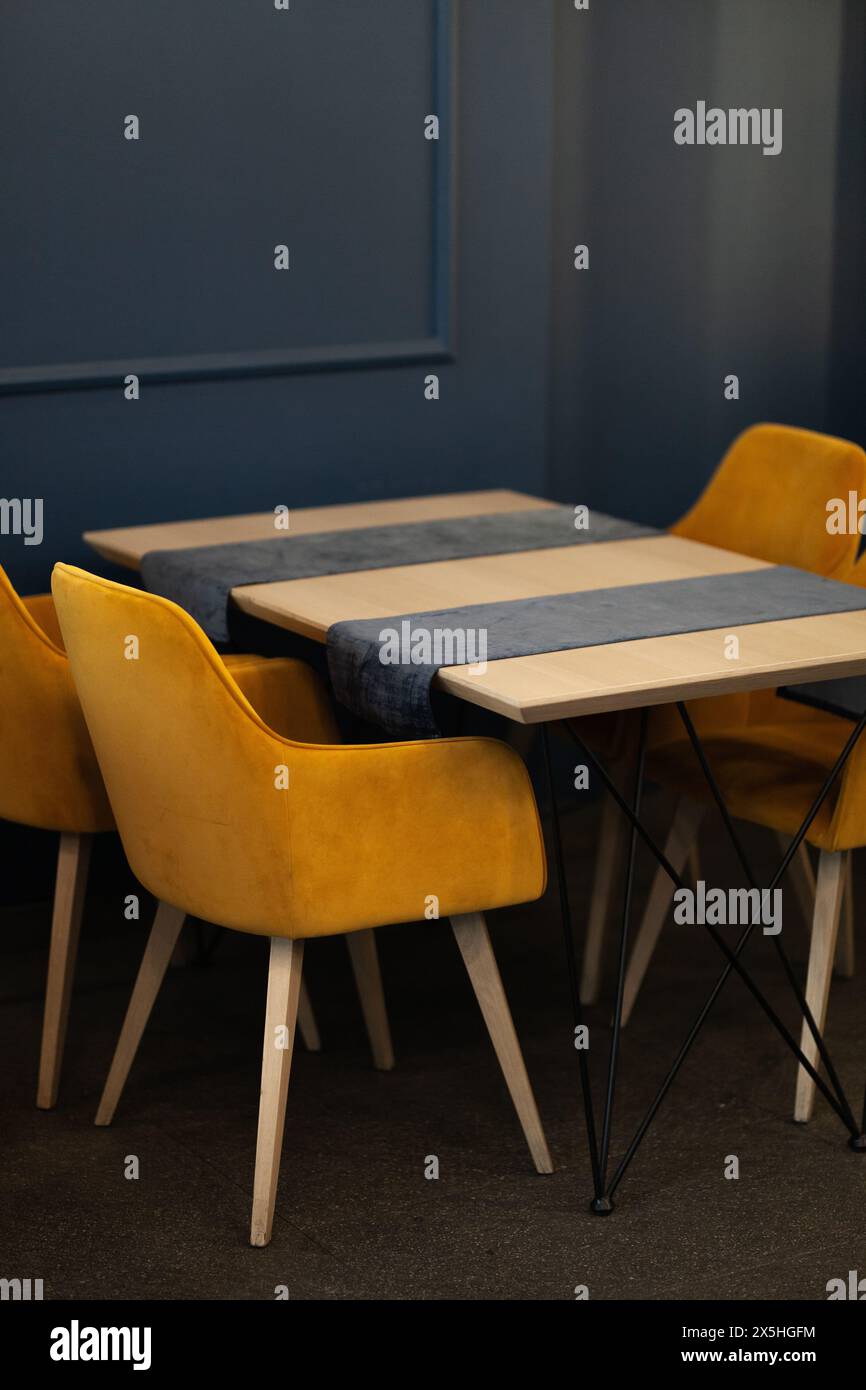 Modernes Café mit goldgelben Stühlen, blauen Wänden und schickem minimalistischem Stil für eine entspannte Atmosphäre. Stockfoto