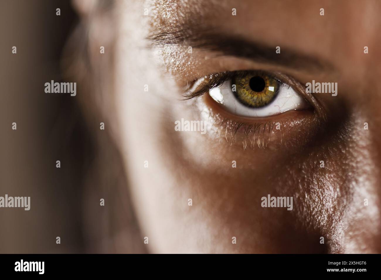 Dieses Bild zeigt eine Nahaufnahme des Auges einer Frau mit detaillierter Textur, natürlicher Haut und einer lebendigen Iris, die einen starken und fokussierten Blick reflektiert. Stockfoto