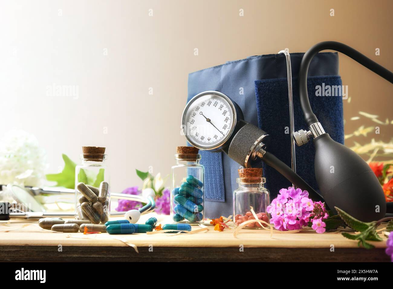 Konzept pflanzlicher Naturheilmittel zur Behandlung von Blutdruckproblemen mit Glasflaschen, Blutdruckmessgerät und Holzblüten Stockfoto