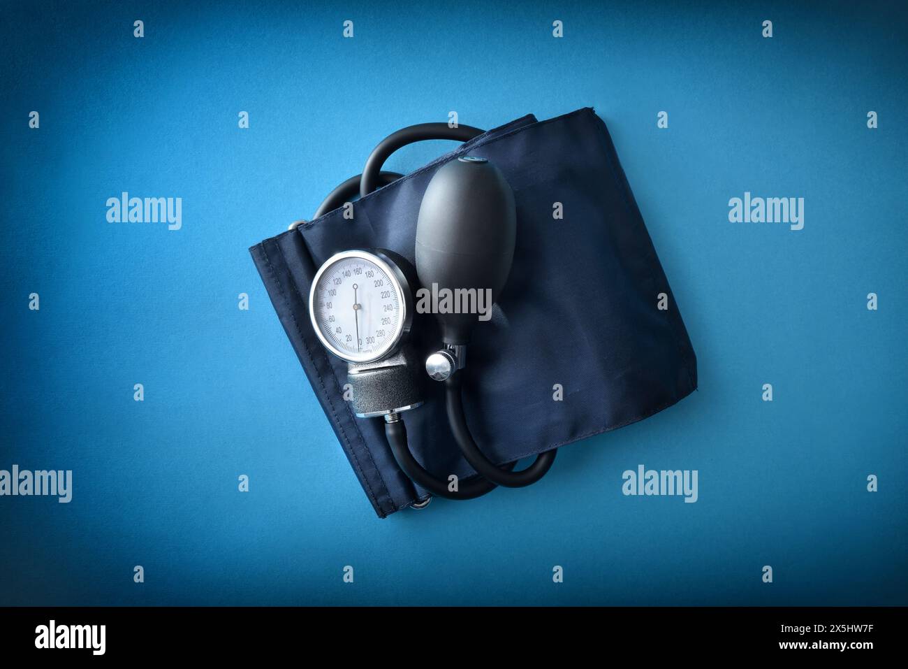 Detailansicht des manuellen Blutdruckmessgeräts mit blauer Manschette, isoliert auf blau. Draufsicht. Stockfoto