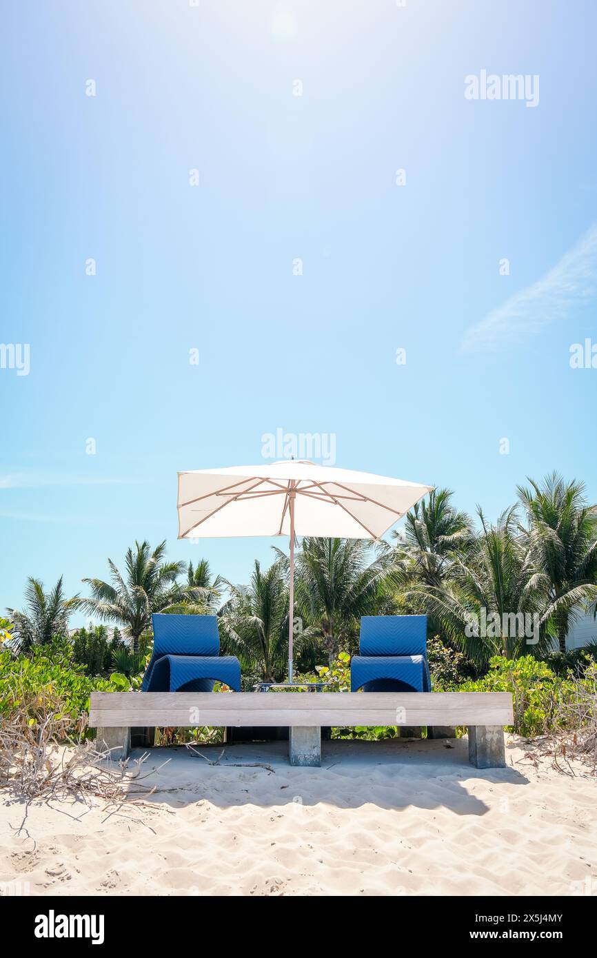 Zwei blaue Liegestühle und Sonnenschirm am Strand Stockfoto