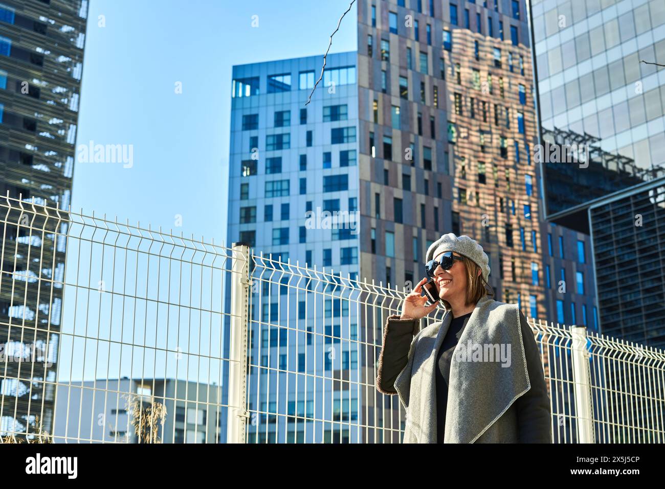 Fröhliche Frau am Telefon, moderner urbaner Hintergrund Stockfoto