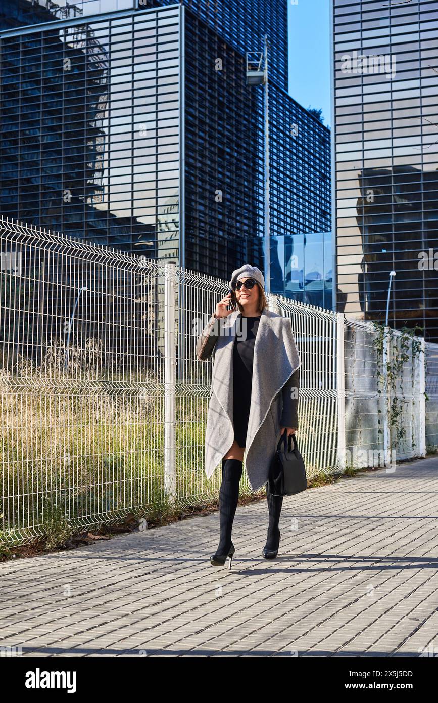 Fröhliche Frau am Telefon, moderner urbaner Hintergrund Stockfoto