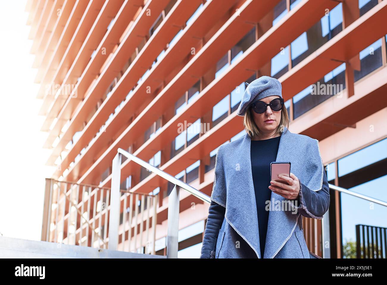 Modische Frau mit Smartphone in der Stadt Stockfoto