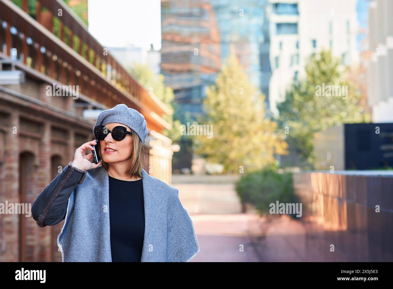 Fröhliche Frau am Telefon mit Stadtbild im Hintergrund Stockfoto