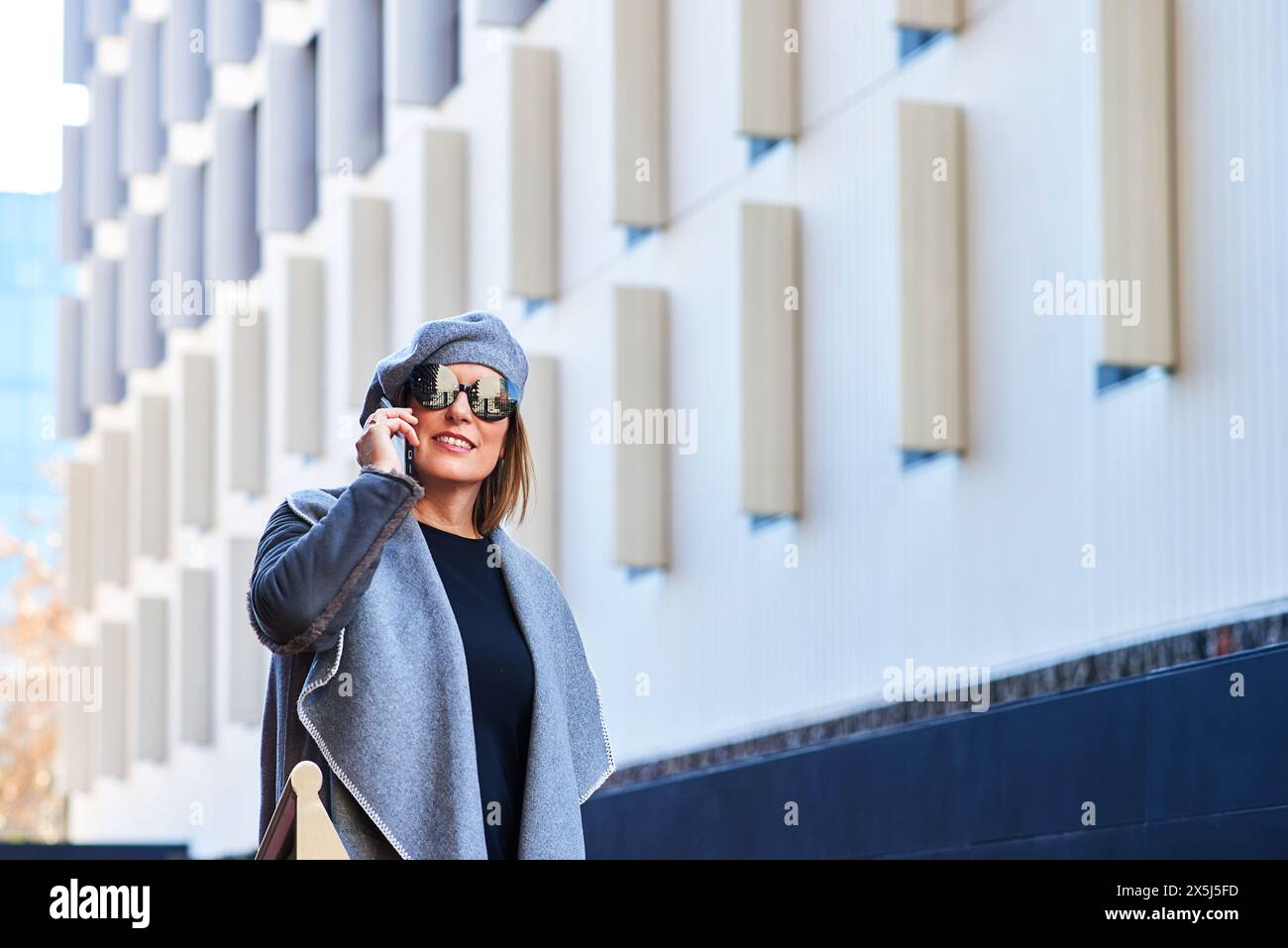 Fröhliche Frau am Telefon mit Stadtbild im Hintergrund Stockfoto