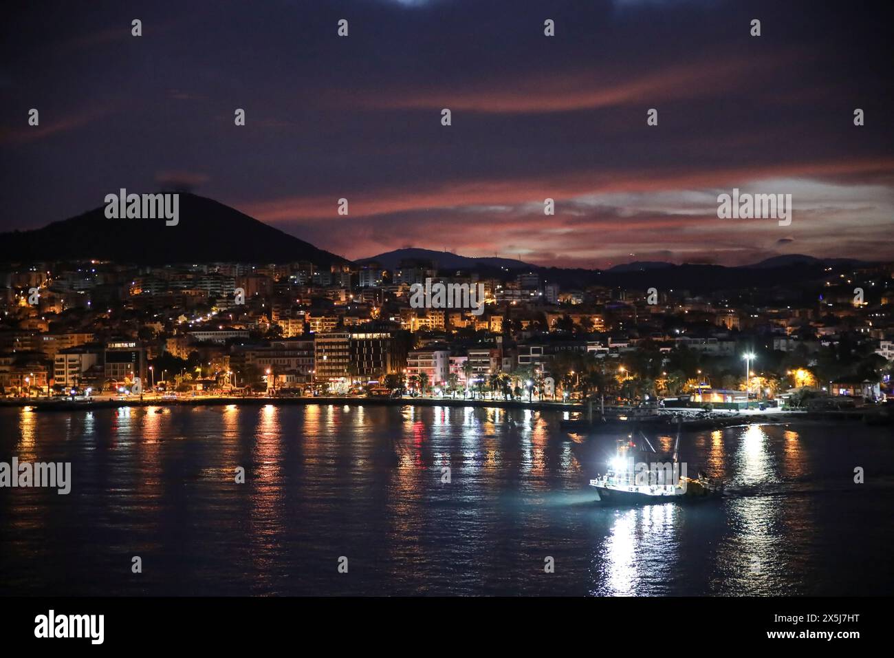 Kusadasi, Türkei. Türkische Riviera. Schlepper auf dem Meer in der Nähe von Uferstadt mit Bergen und dem rosa Sonnenaufgang Stockfoto