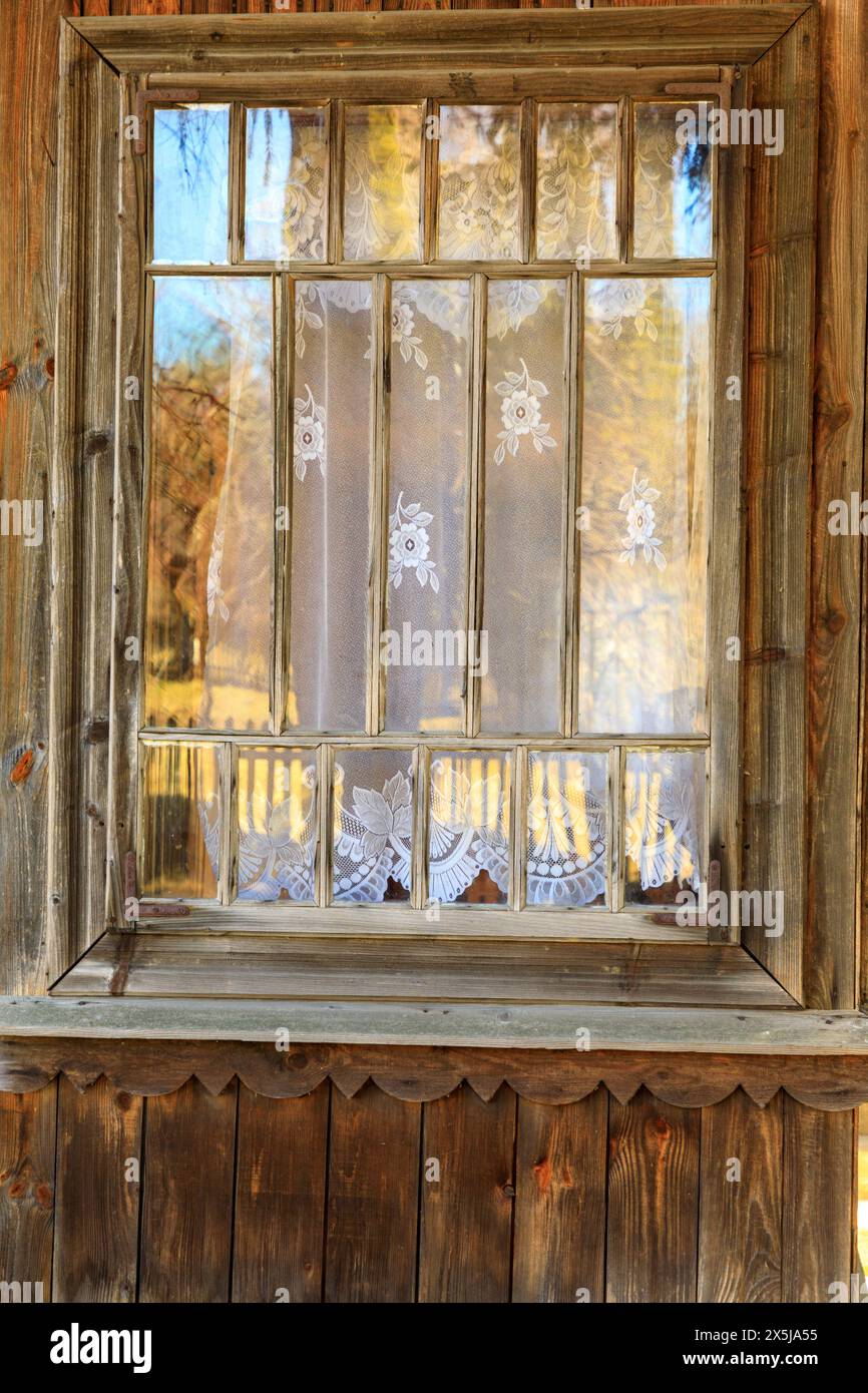 Ukraine, Kiew, Kiew. Abstrakte Holzverkleidung und traditioneller Spitzenfenstervorhang. Das Dorf Olchovsky außerhalb der Stadt. Stockfoto