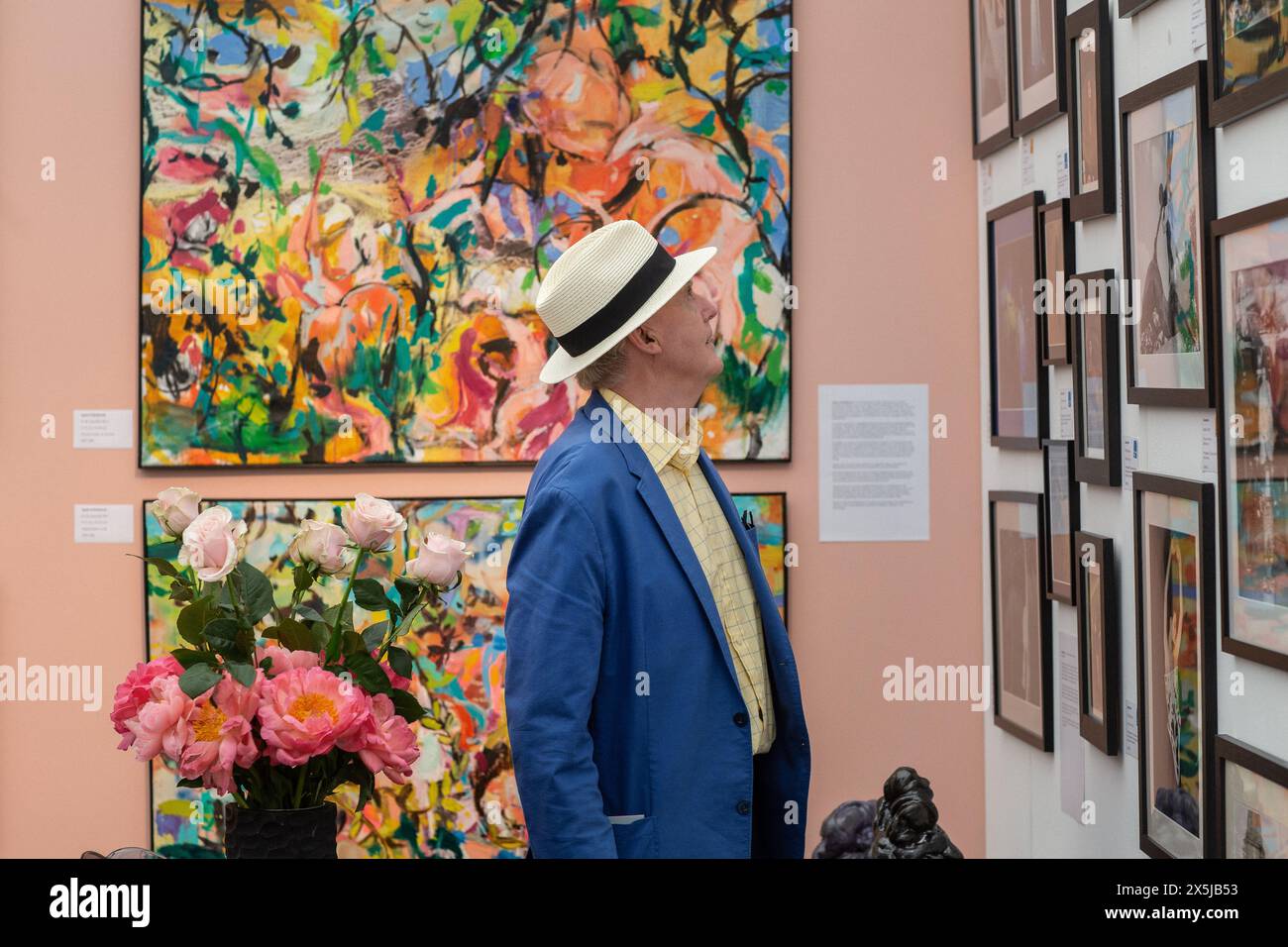 Mann mit Strohhut, der Gemälde am Eröffnungstag der Kunstmesse beobachtet . Stockfoto