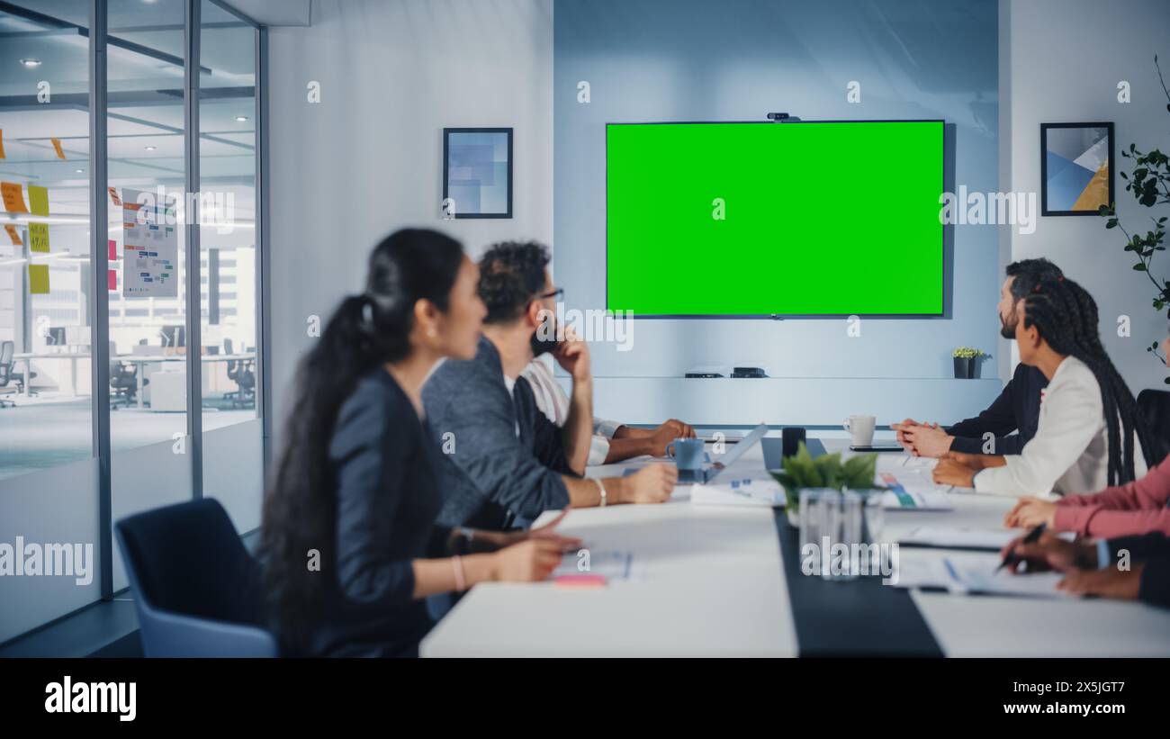 Multi-ethnische Büro Konferenzraum Meeting: Vielfältiges Team erfolgreicher Manager, Führungskräfte sprechen, verwenden Green Screen Chroma Key TV. Geschäftsleute, die in eCommerce Startup investieren. Stockfoto