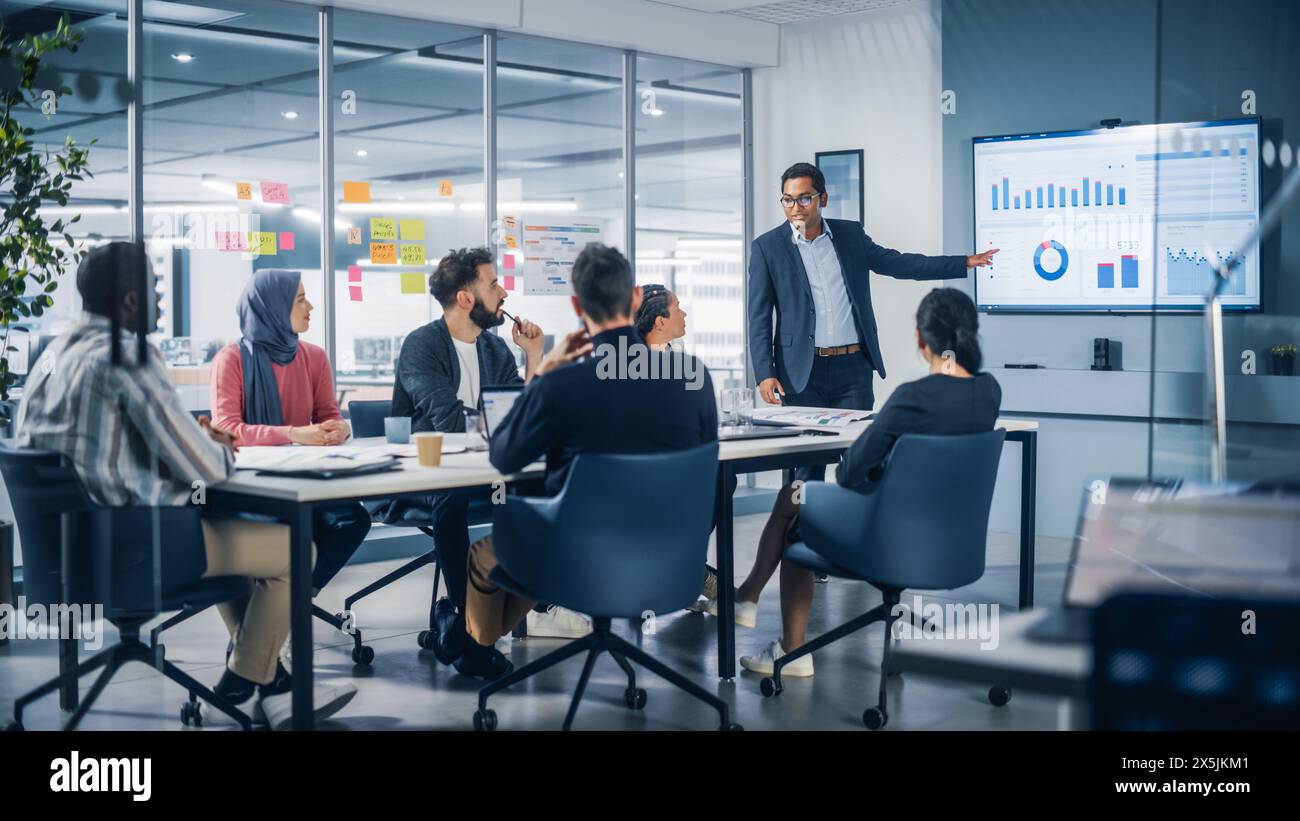 Präsentation im Multi-Ethnic Office Konferenzraum. Treffen verschiedener Jungunternehmer, Spezialisten, Talking, TV für Infografiken. Geschäftsleute entwickeln E-Commerce Startup. Stockfoto