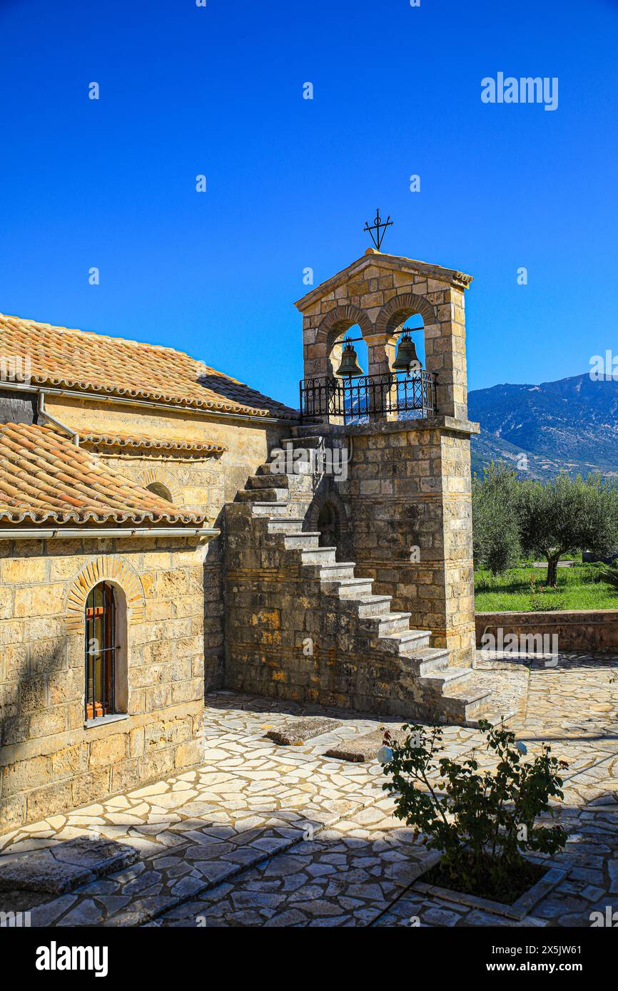 Griechenland. Griechische Steinkirche mit Ziegeldach, Bogenfenstern, Glockenturm und Olivenhain Stockfoto
