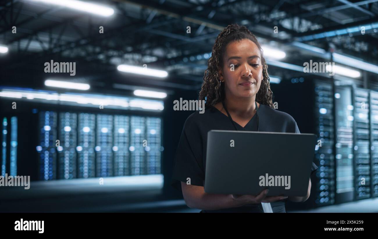 Büro: Erfolgreiche Geschäftsfrau in stilvoller Kleidung, die am Laptop arbeitet und auf den Bildschirm blickt. Stilvolle Führungskraft, die lange am Computer arbeitet, um beste Ergebnisse zu erzielen Stockfoto