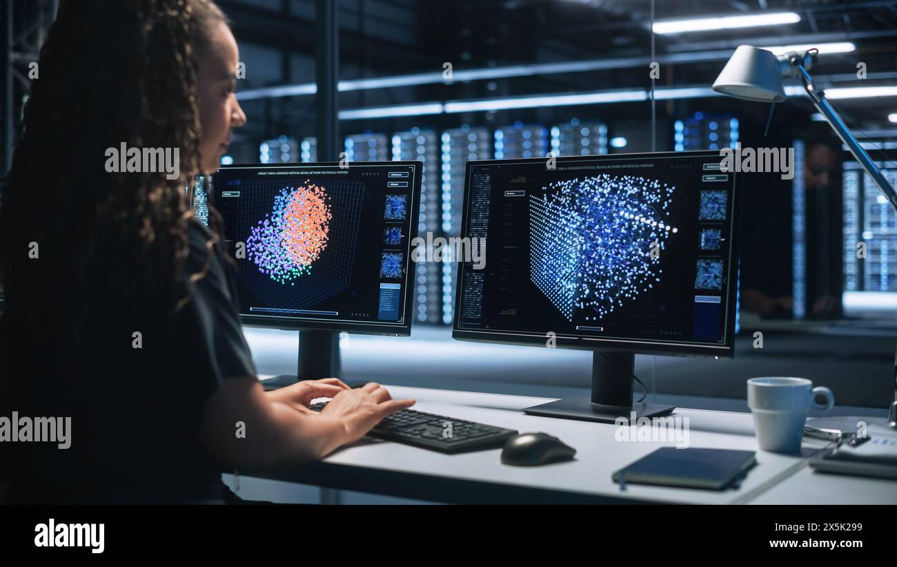Hi-Tech AI Research Center afroamerikanische weibliche IT-Ingenieurin arbeitet an einem neuronalen Netzwerk-Projekt, sie verwendet zwei Personal Computer, Screen Shows Big Data Graphics, Futuristic Machine Learning Concept Stockfoto