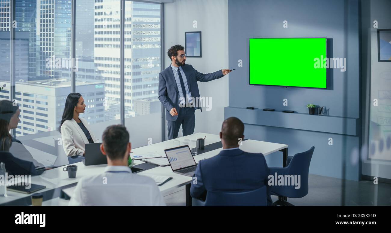 Office Conference Room Meeting Präsentation: Motivierte kaukasische Geschäftsleute sprechen mit Green Screen Chroma Key Wall TV. Erfolgreiche Präsentation eines Produkts bei Gruppe von Multi-ethnischen Investoren Stockfoto