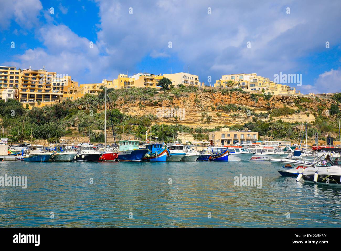 Gozo, Malta. Gozo Yachthafen, farbenfrohe Luzzu-Boote in der Bucht mit Blick auf Kalksteinwohnungen Stockfoto