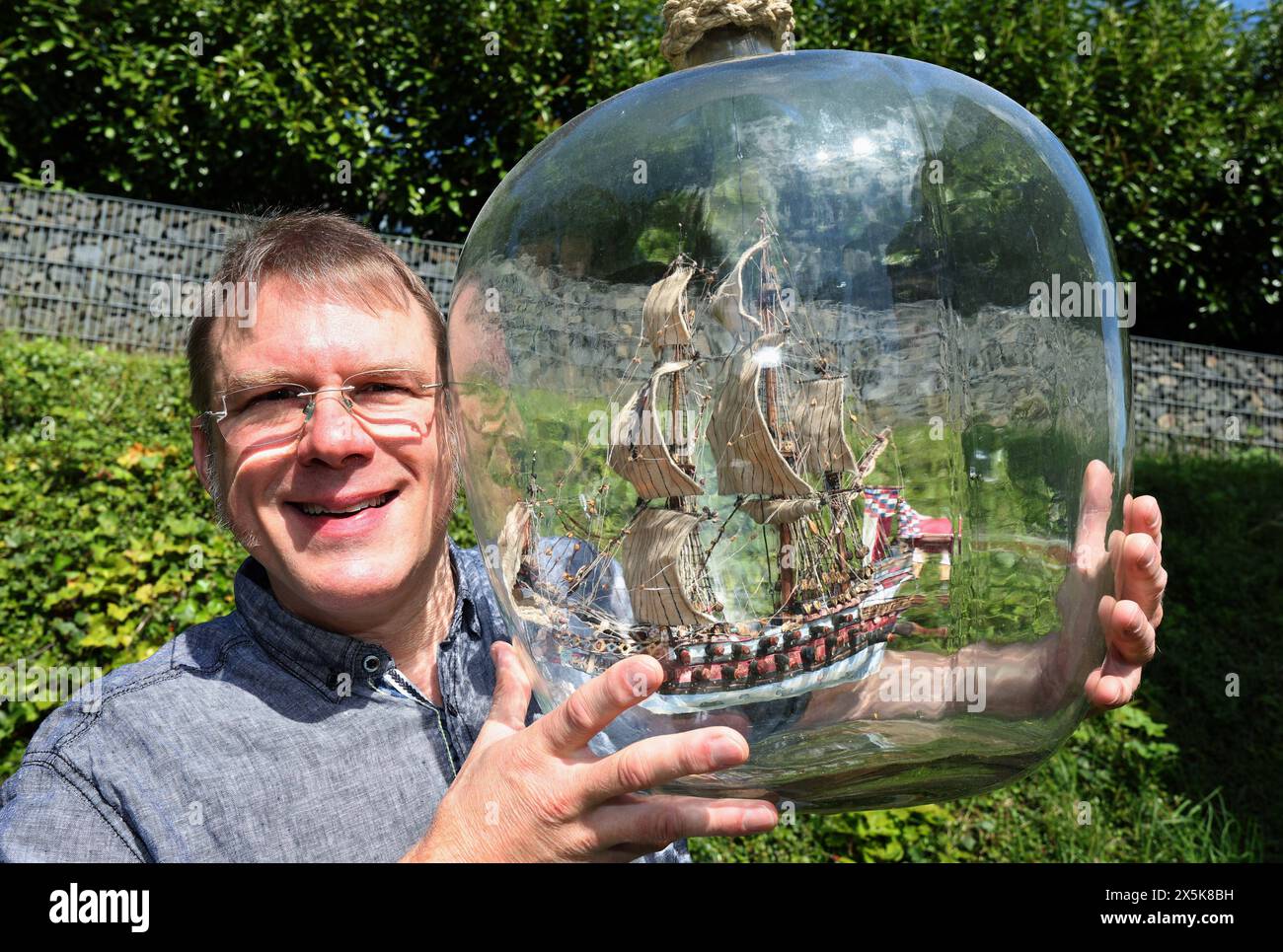 Bad Kissingen, Deutschland. Mai 2024. Matthias Schultz hält ein 40 Zentimeter hohes und 38 Zentimeter langes Schiff in einer von ihm gebauten Flasche, die in einem 50-Liter-Fermentationsballon hängt. Der Modellbauer will mit dem „größten freischwimmenden Schiff der Welt in einer Flasche“ ins Guinness-Buch der Rekorde einsteigen. Quelle: Karl-Josef Hildenbrand/dpa/Alamy Live News Stockfoto