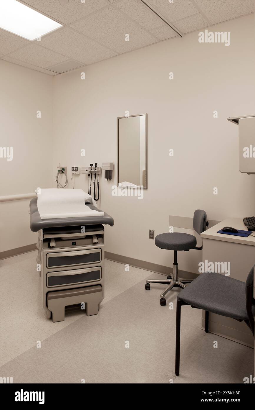 Ein Untersuchungsraum in einem Krankenhaus, mit Behandlungstisch, Patientenbett, Hocker und Stuhl. Stockfoto