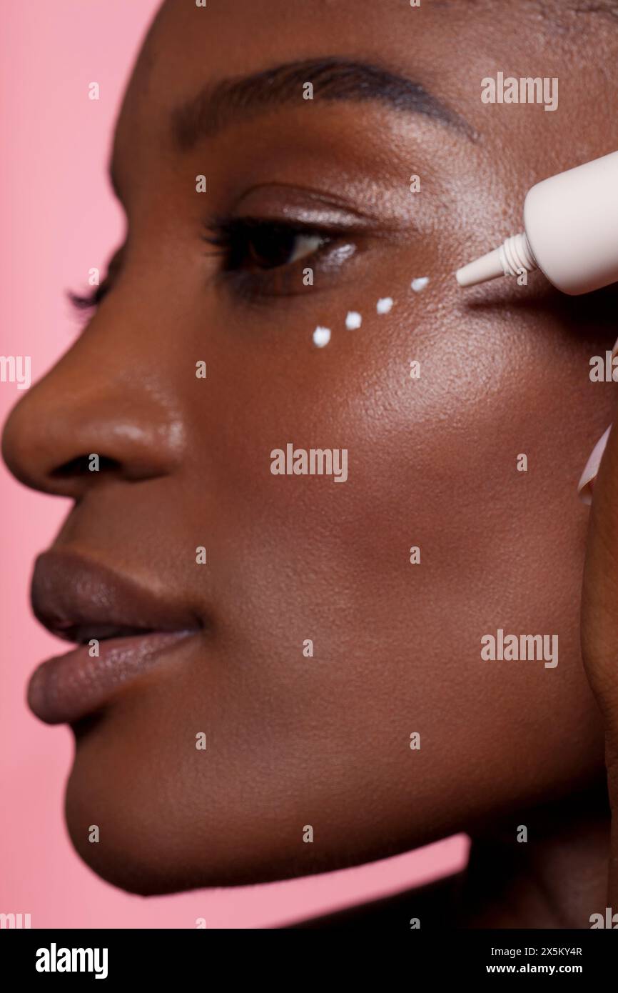 Junge Frau Augencreme anwenden Stockfoto